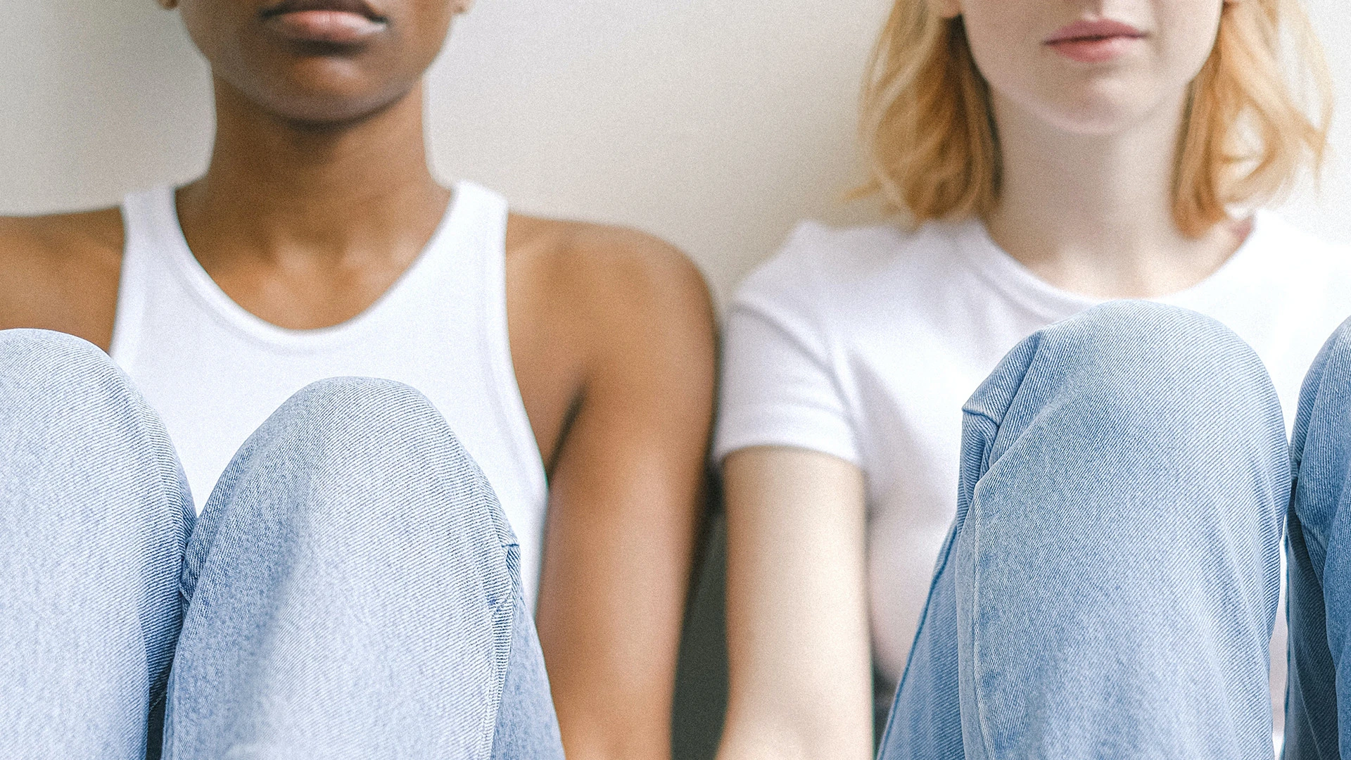 Two women sat side by side against a wall